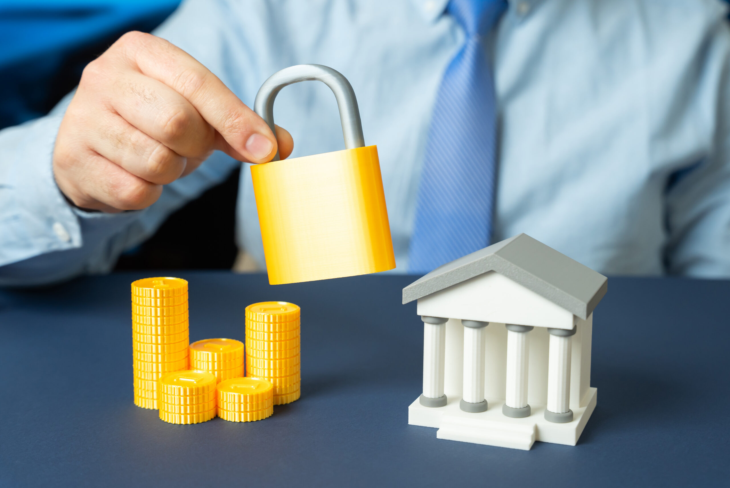 A bank and a padlock in the hands of a man in a tie. Bank protection and cybersecurity strategy