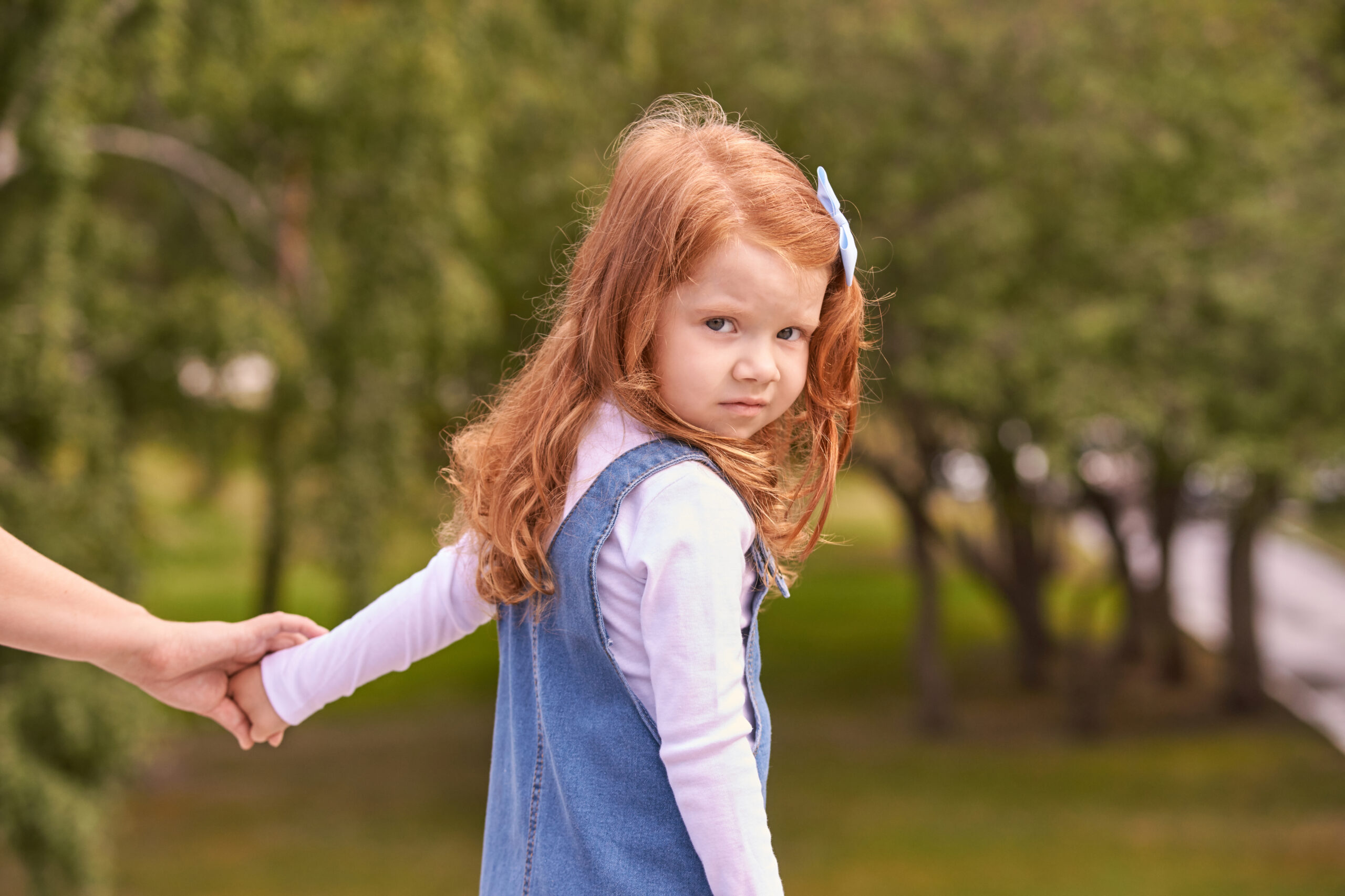 Young caucasian female child with red hair holding hand outdoors in park